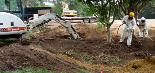 Bobcat continually takes blown soil out of the trench and stockpiles it.